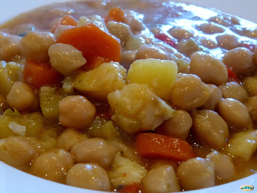 Primer plano de potaje de garbanzos con rodajas de zanahoria y trozos de patata en caldo dorado