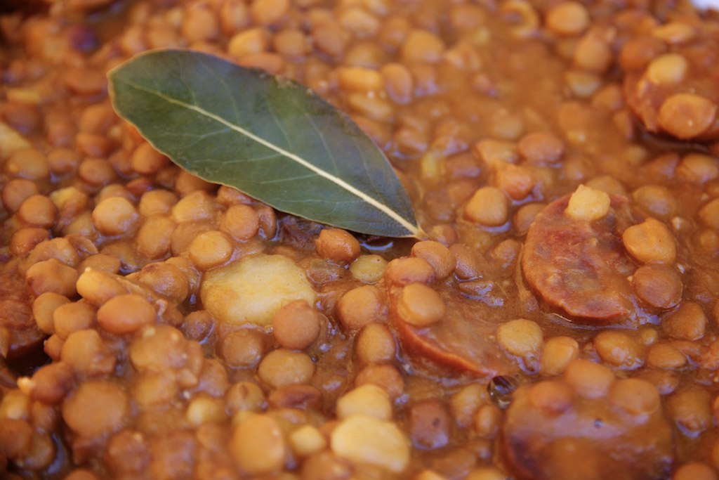 Potaje de lentejas con rodajas de chorizo, trozos de patata y una hoja de laurel